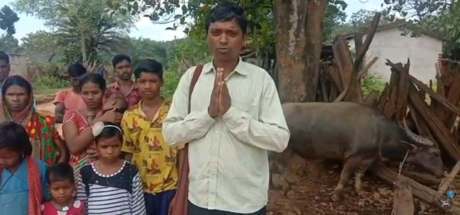 A man greeting a village gathering with folded hands