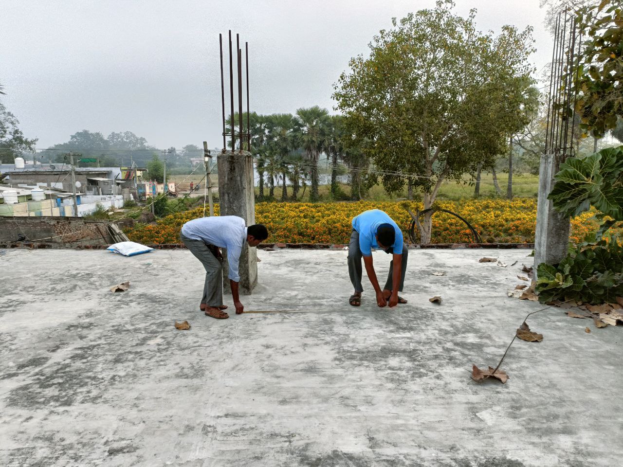 Two workers tying steel on a building roof under construction
