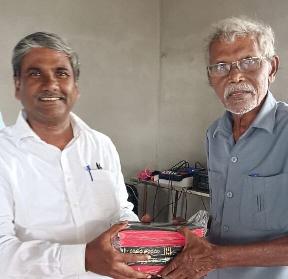Two ministry workers holding Telugu Bibles at the pastors conference